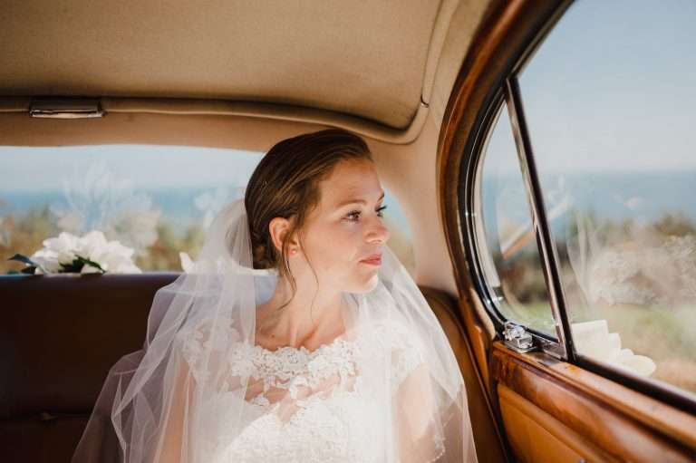 Bride waiting to be let out of vintage car - The Top 3 Tips For Posing Naturally in Your Wedding Photos