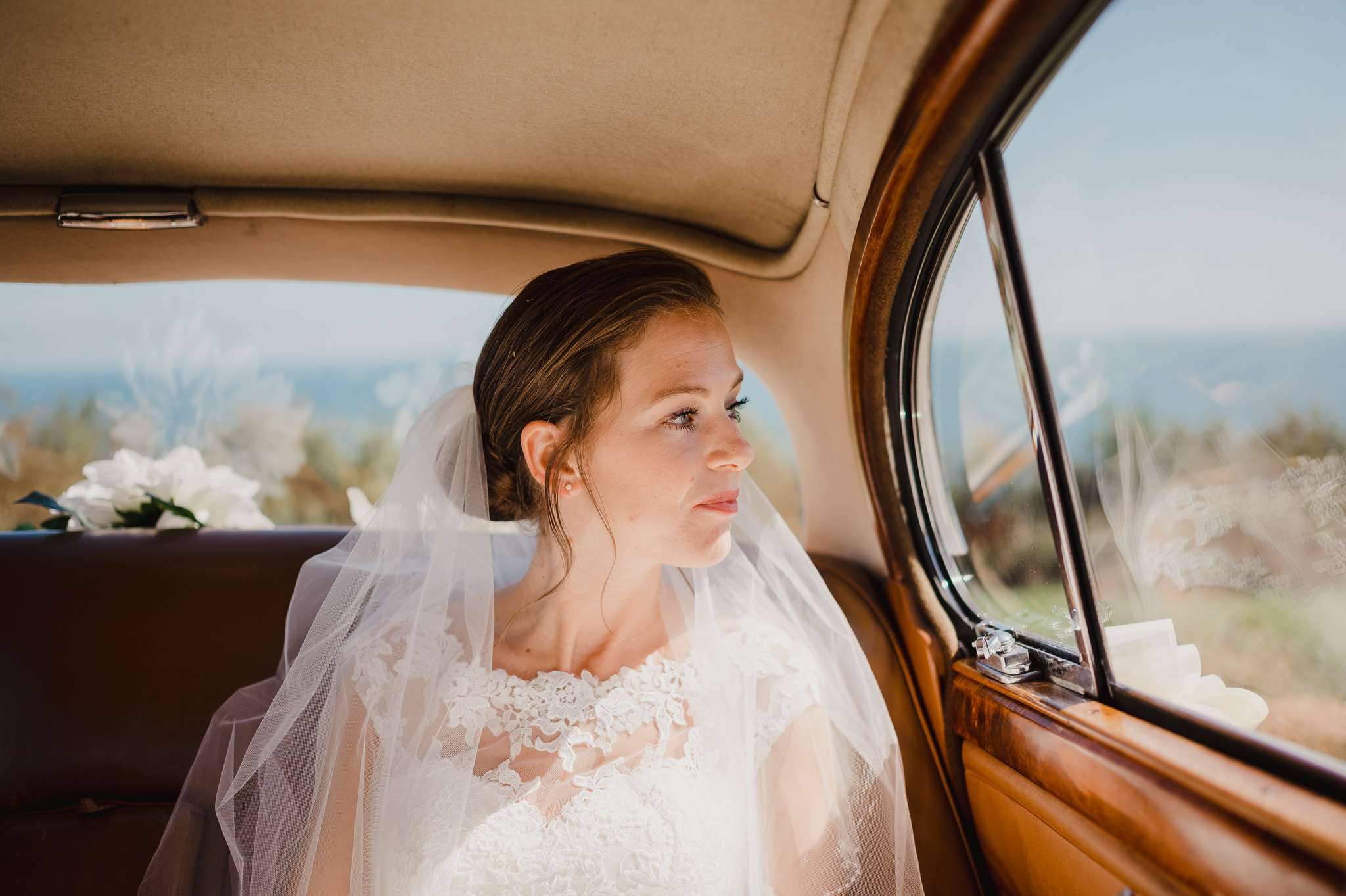 Bride waiting to be let out of vintage car - The Top 3 Tips For Posing Naturally in Your Wedding Photos