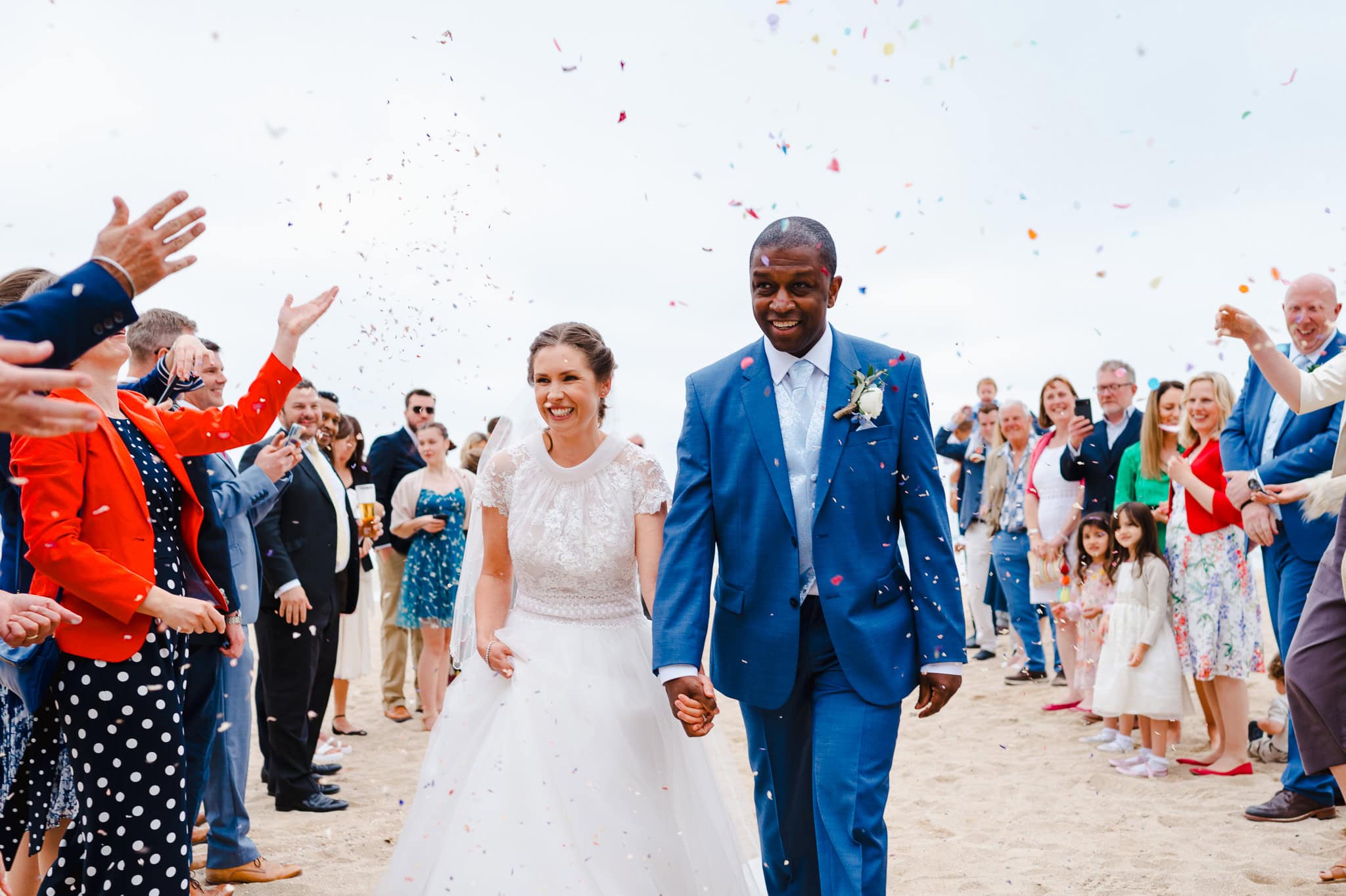 Bride and groom walk down the confetti aisle at Lusty Glaze - Top 5 Coastal Wedding Venues In Cornwall