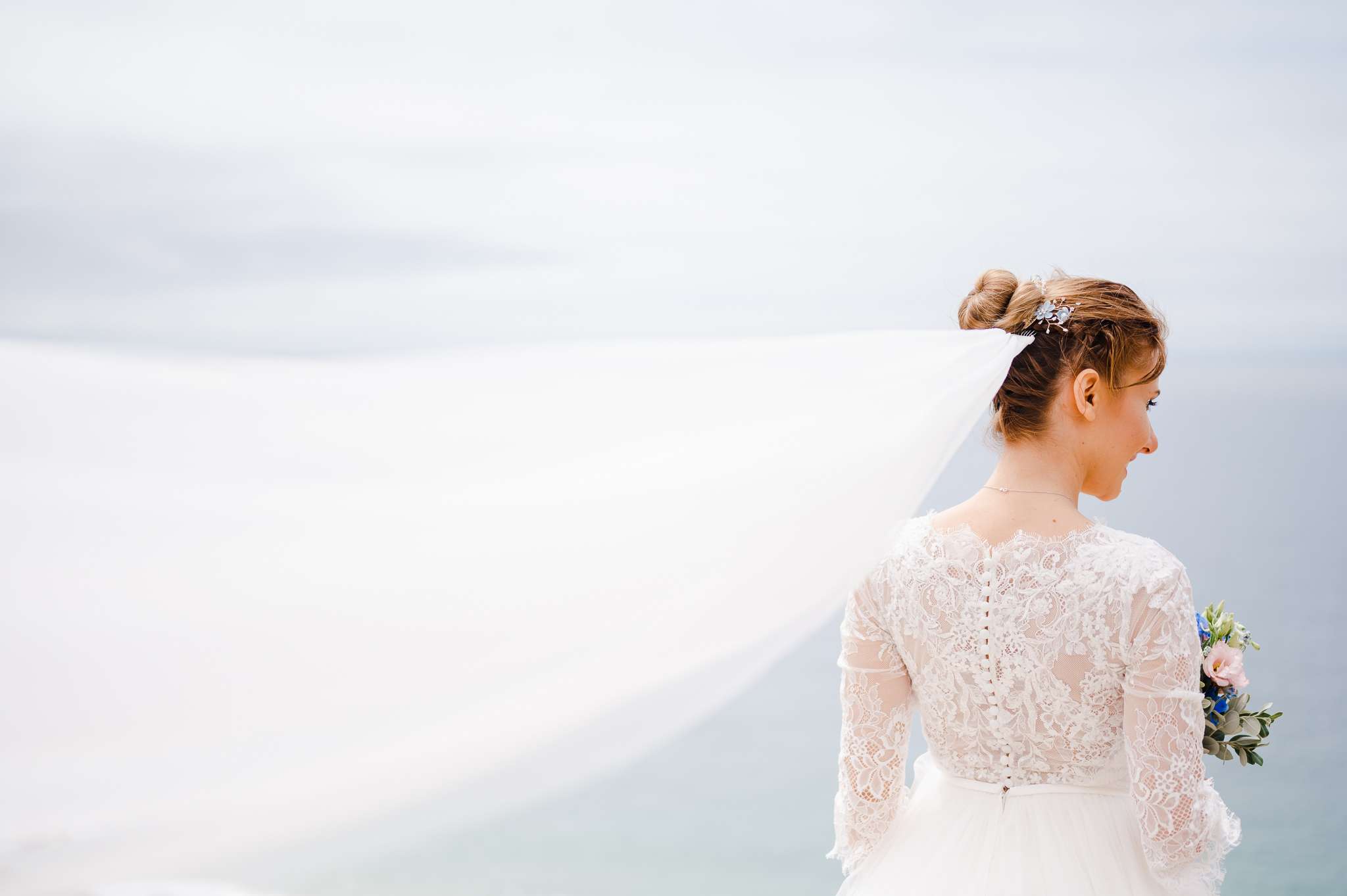 Dress veil blowing in the wind while the bride looks out to sea - 14 Tips to Help You Find the Perfect Wedding Dress
