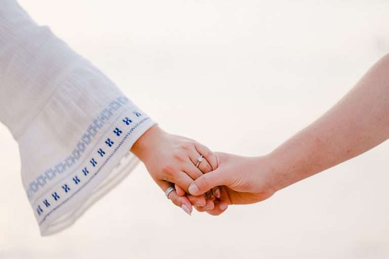 Newly Engaged couple holding hands celebrating their engagement chapter - What To Do Now You're Engaged