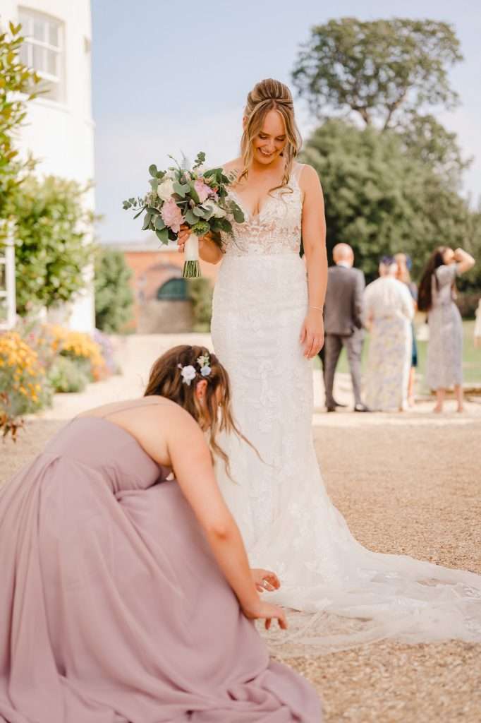 Bride having her dressed fluffed up at Rockbeare Manor - The Questions You Need To Ask Your Wedding Venue | Cornwall Wedding Photographer