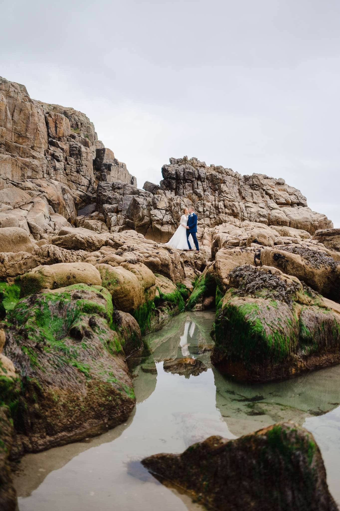 Wedding Couple standing on the rugged coastline by Rinsey, Cornwall - How To Pick Your Perfect UK Wedding Venue - Your Ultimate Guide