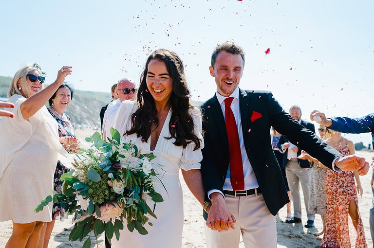 Happy couple celebrate Small wedding at Watergate Bay, Cornwall with lots of confetti