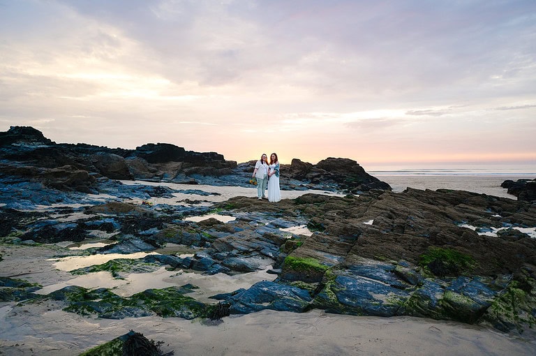 A beautiful red sunset behind the couple as they pose for a couple photo on the rock pools at Gwithian, Cornwall