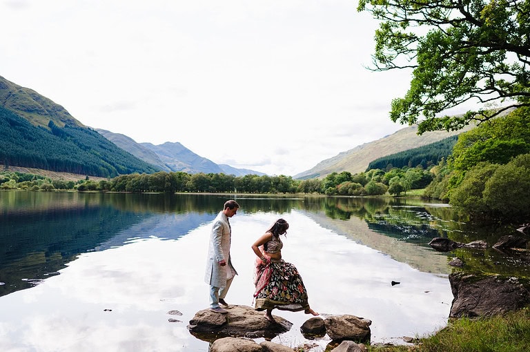 Happy couple celebrate their elopement wedding in Scotland. They're hopping across some borders on the beautiful Loch