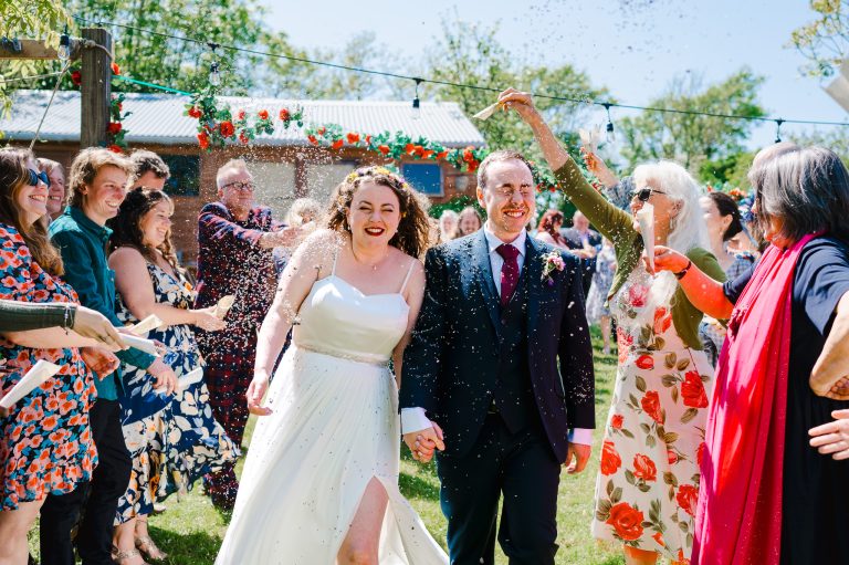 Confetti Time as the wedding guest chuck loads of wedding confetti over the bride and groom outside on a summers day