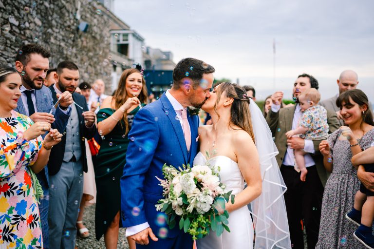 Wedding couple kiss under bubbles - Blog Post -Creating A Unique Wedding Venue: Inspirational Themes and Decor Ideas
