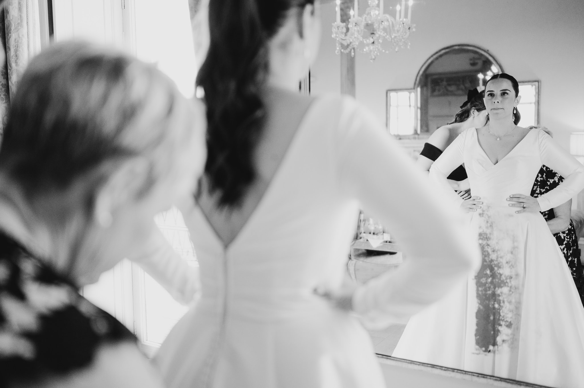 Bride looking into the mirror as mother of the bride is doing up her wedding dress - 10 Creative Ways To Include Social Media In Your Wedding