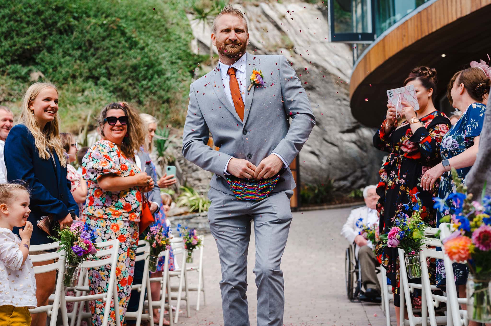 Flower man enters wedding ceremony throwing flower petals