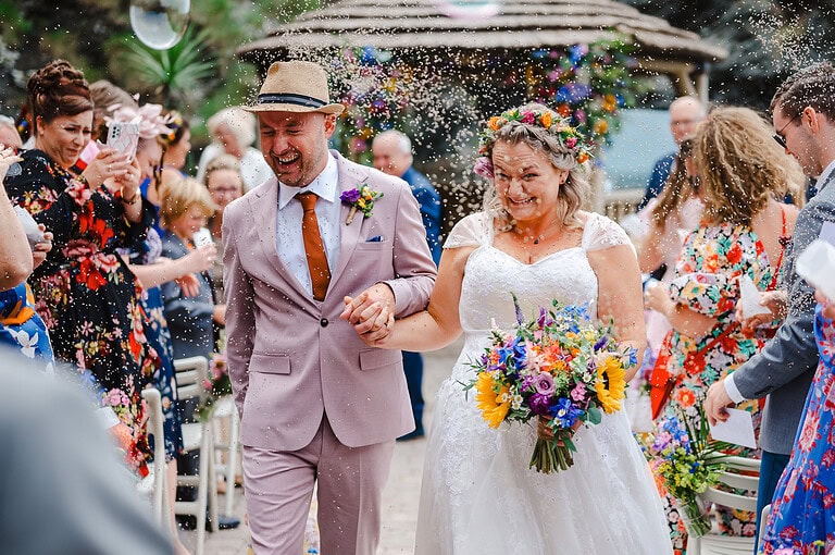 Wedding Confetti thrown high as the bride and groom walk back down the aisle at Tunnels Beaches Wedding, Devon