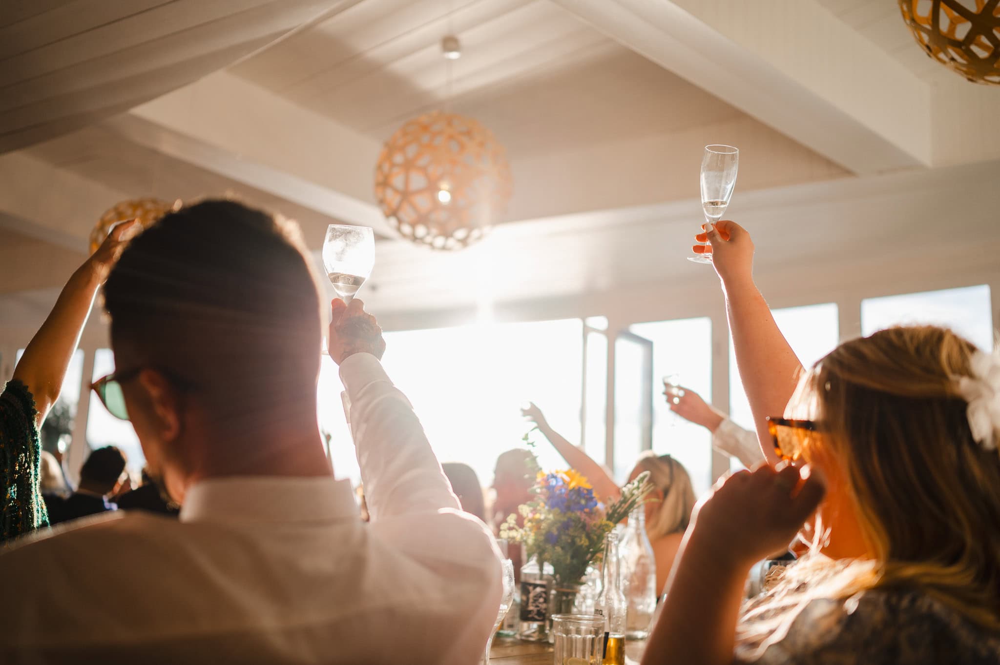 Wedding guests raising a glass as the sun shines through