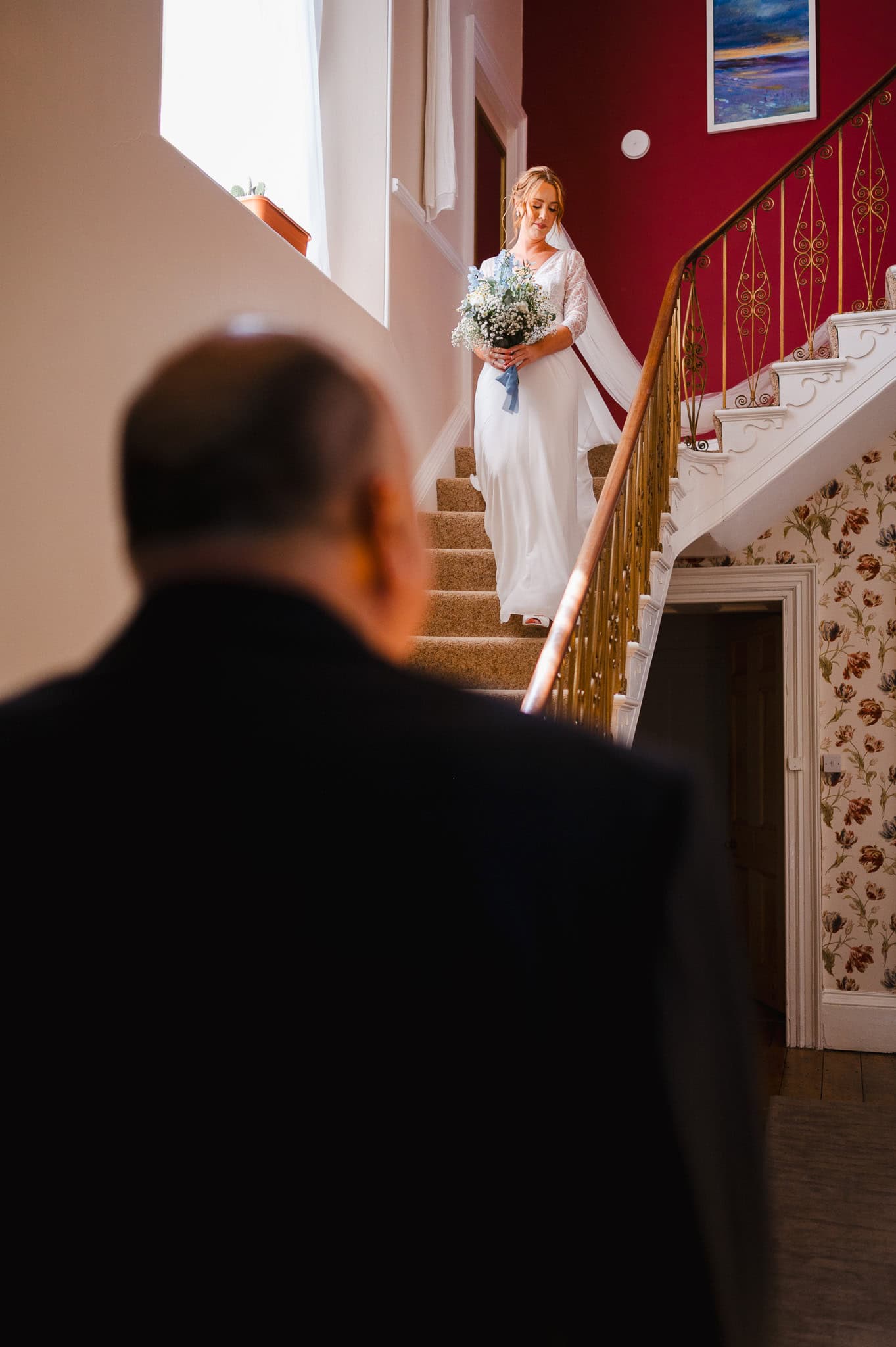 Bride walking down the stairs to have a first look with her father