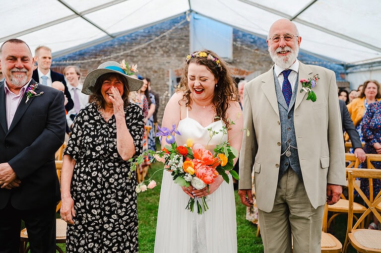 Bride walking down the aisle with mum and dad at a St Austell Marquee Wedding - Wedding Photographer Price