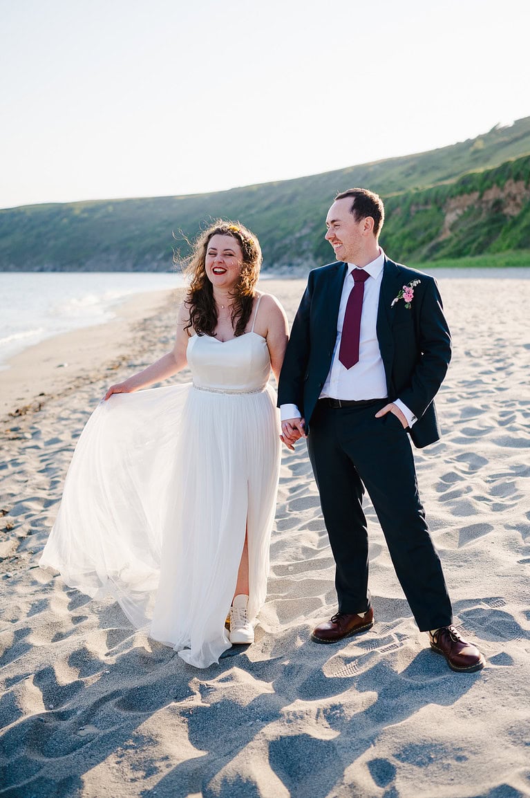 Laughing on a beach as the happy couple celebrate their wedding day - wedding photos cost