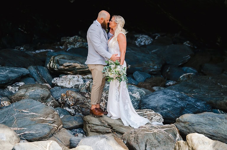 Wedding Couples on the rocks at Lusty Glaze, Newquay celebrating their wedding - average price for a wedding photographer