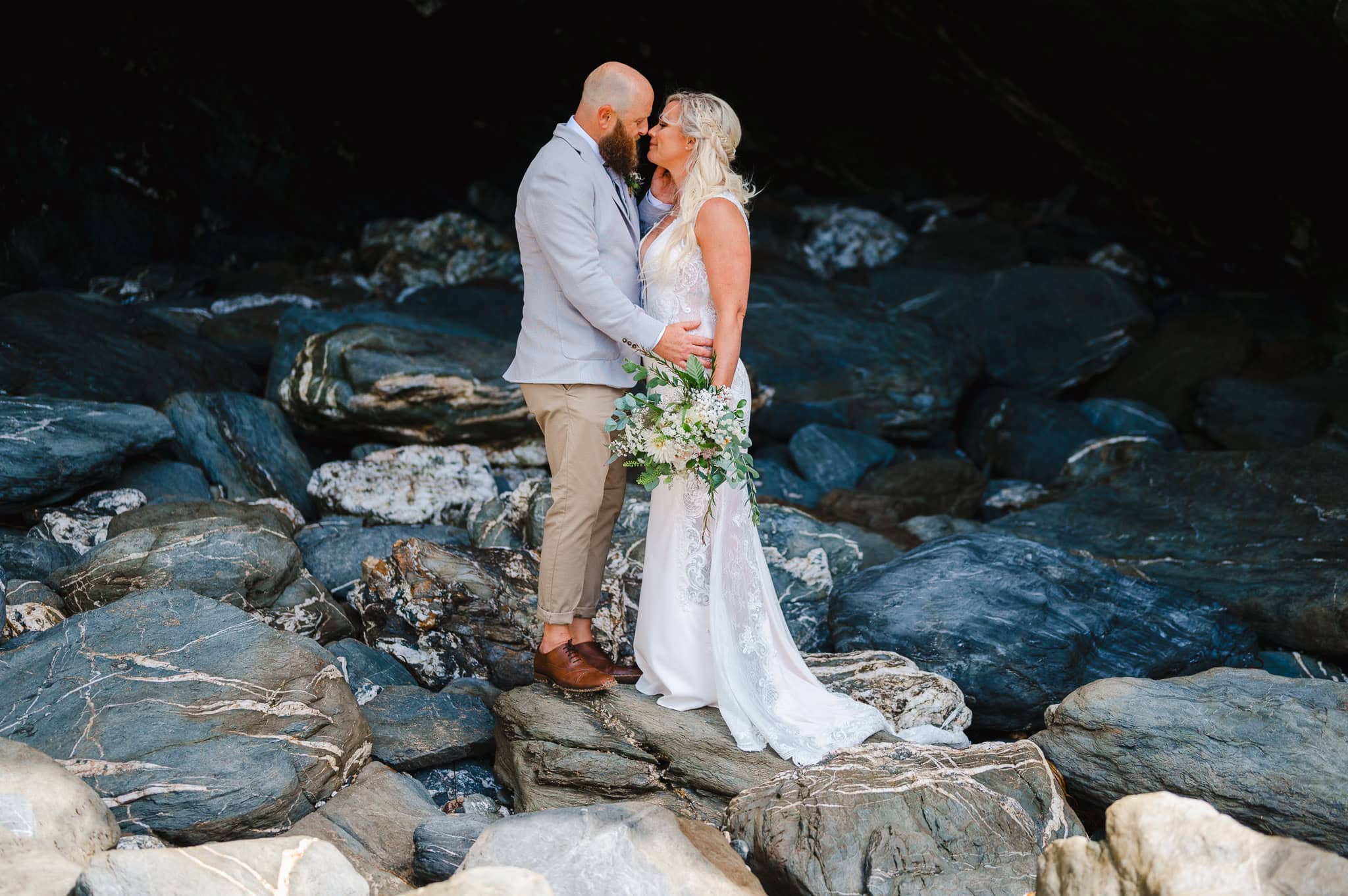 Wedding Couples on the rocks at Lusty Glaze, Newquay celebrating their wedding - average price for a wedding photographer