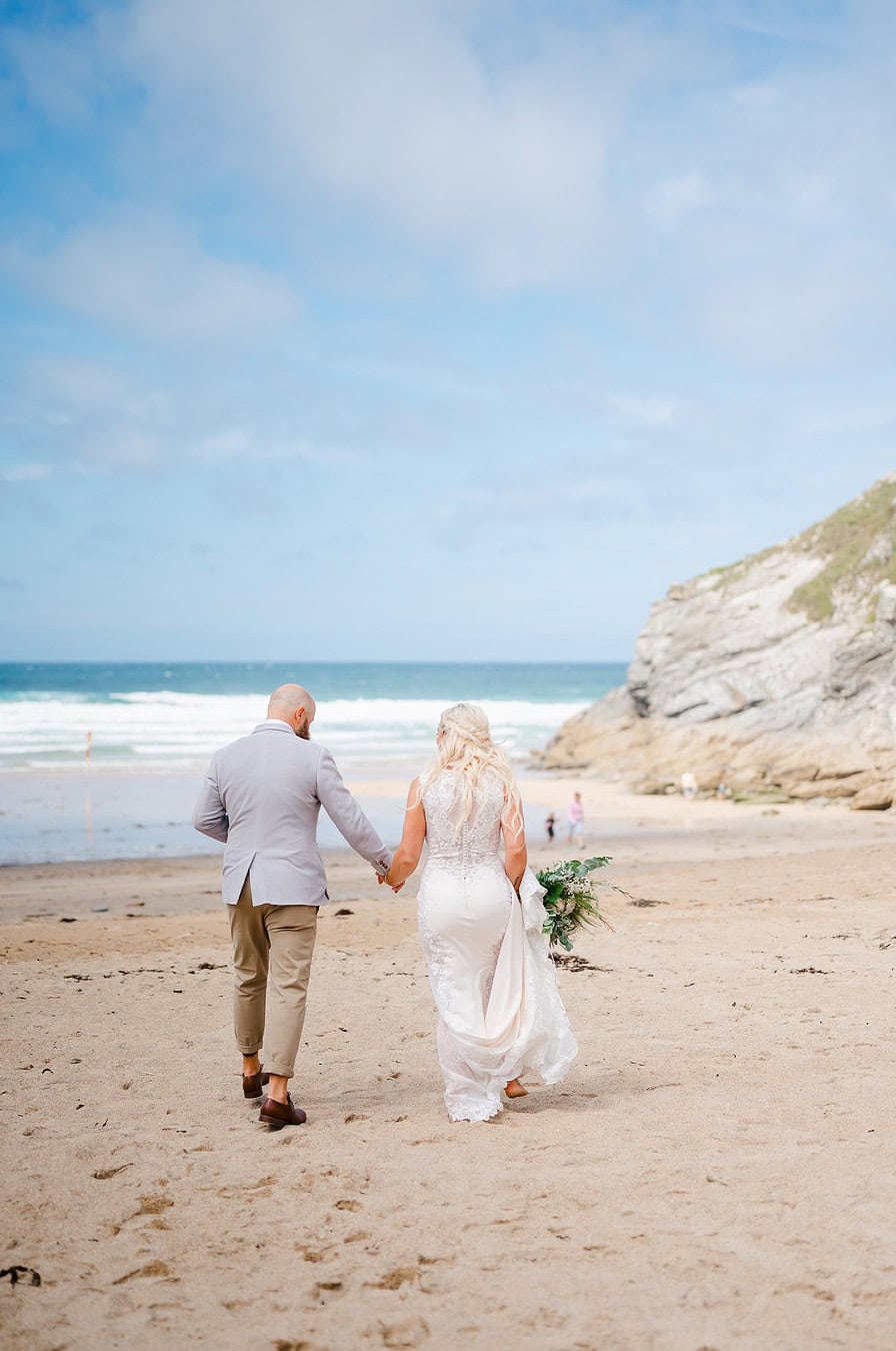 Wedding couple walking along the Lusty Glaze Beach