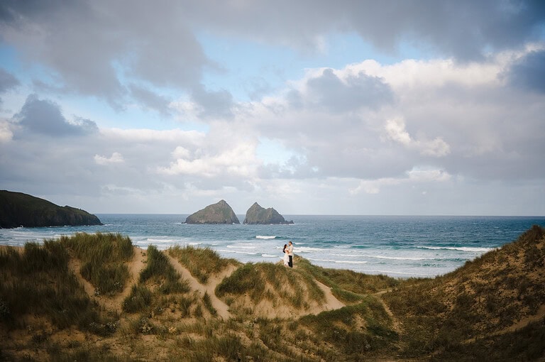 With the sea in the background, the couple stand tall on the sand dunes in front
