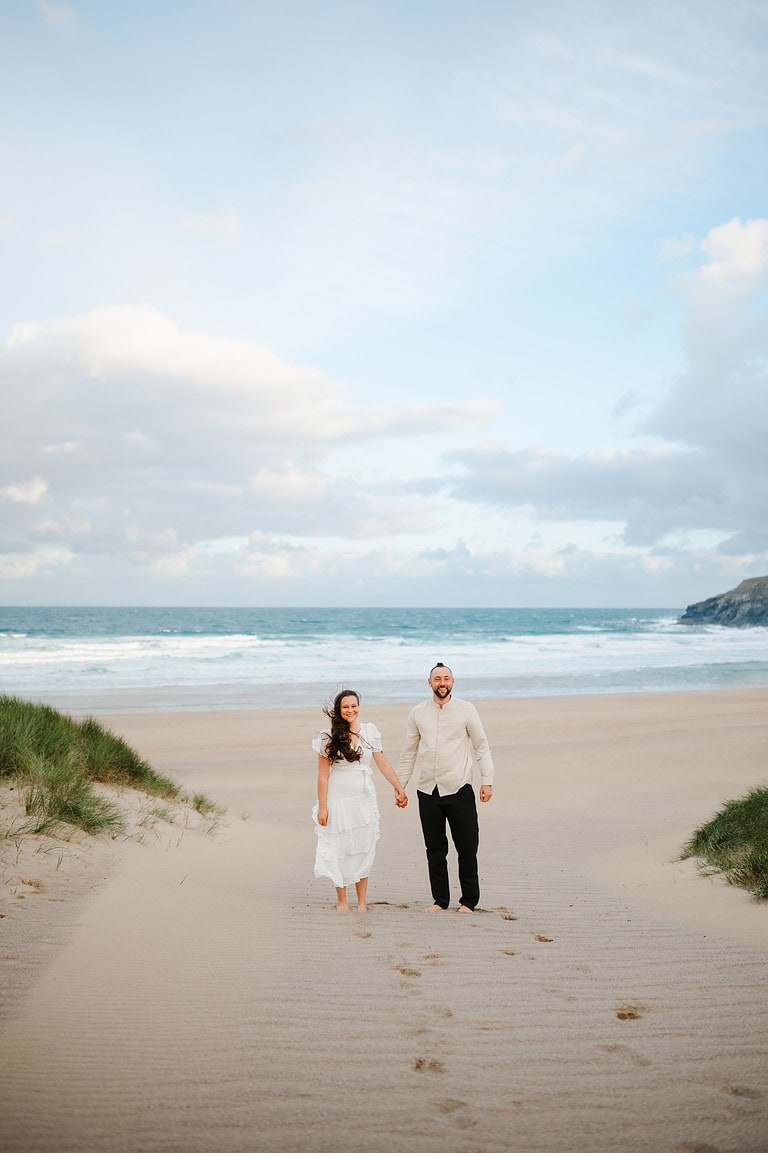 With the sea in the background, the smiling couple look towards the camera as the wind rushes by