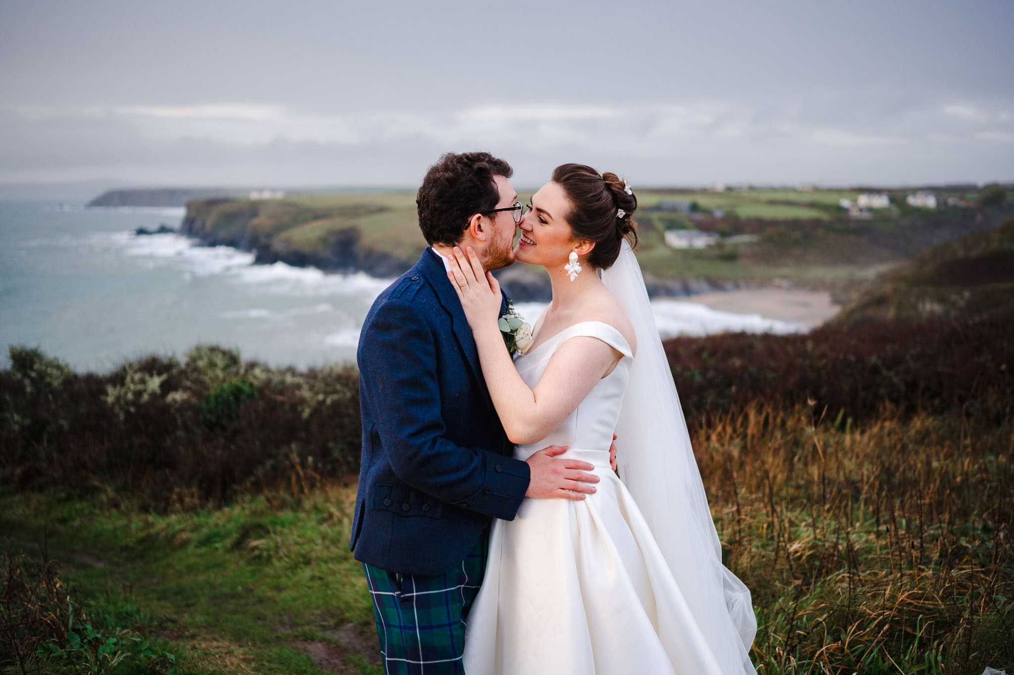 Wedding couple kiss above the sea top at Polurrian during their Autumn Wedding - Autumn Wedding Ideas