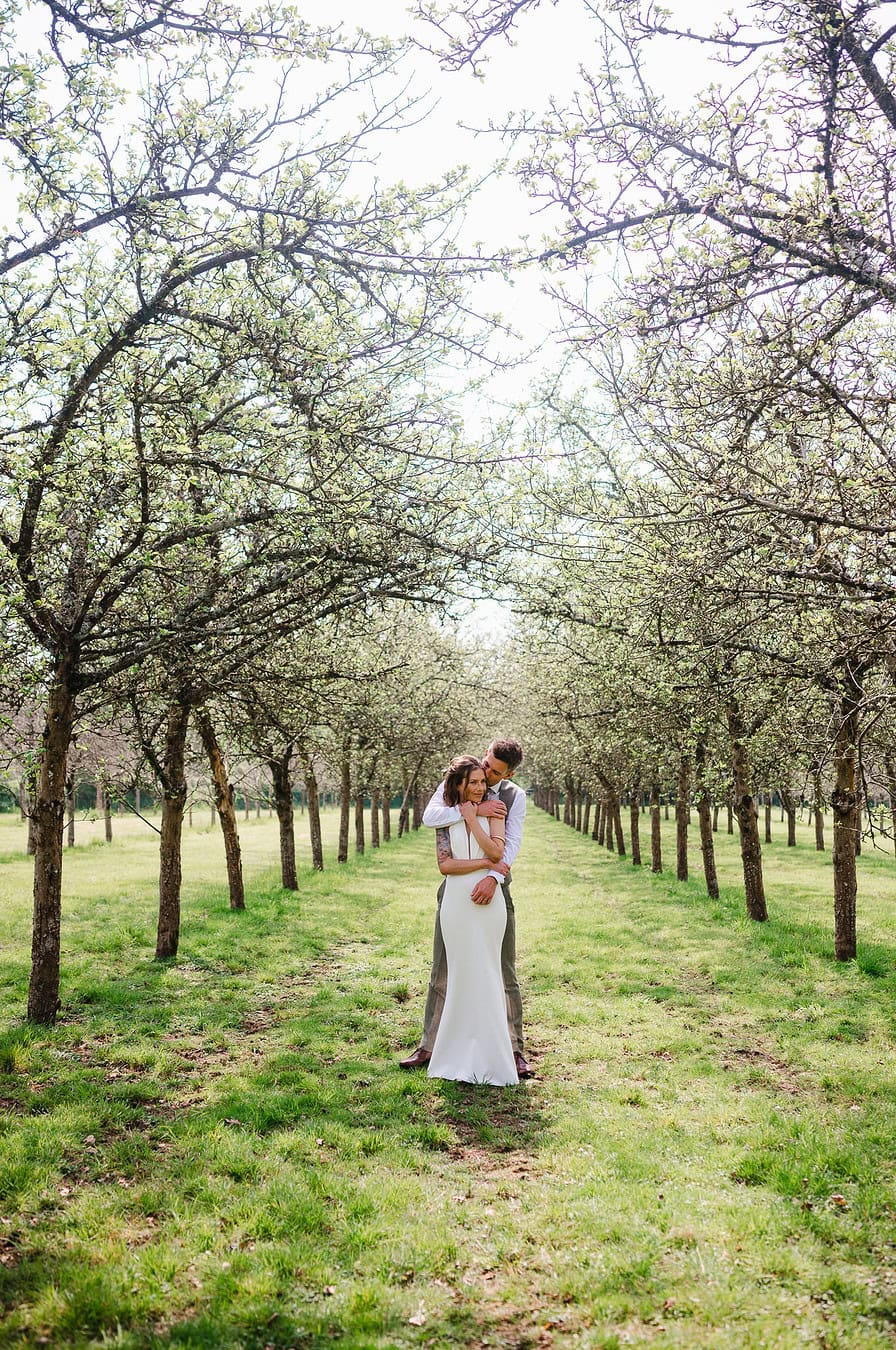 Standing between the apple orchard at Froginwell Vineyard wedding venue - Exeter Wedding Photographer