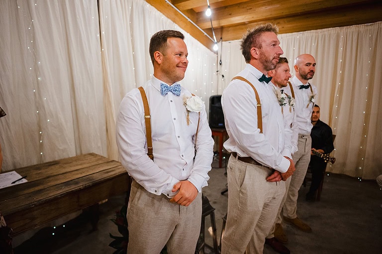 Groom and groomsmen waiting at the end of the aisle for the bride to enter