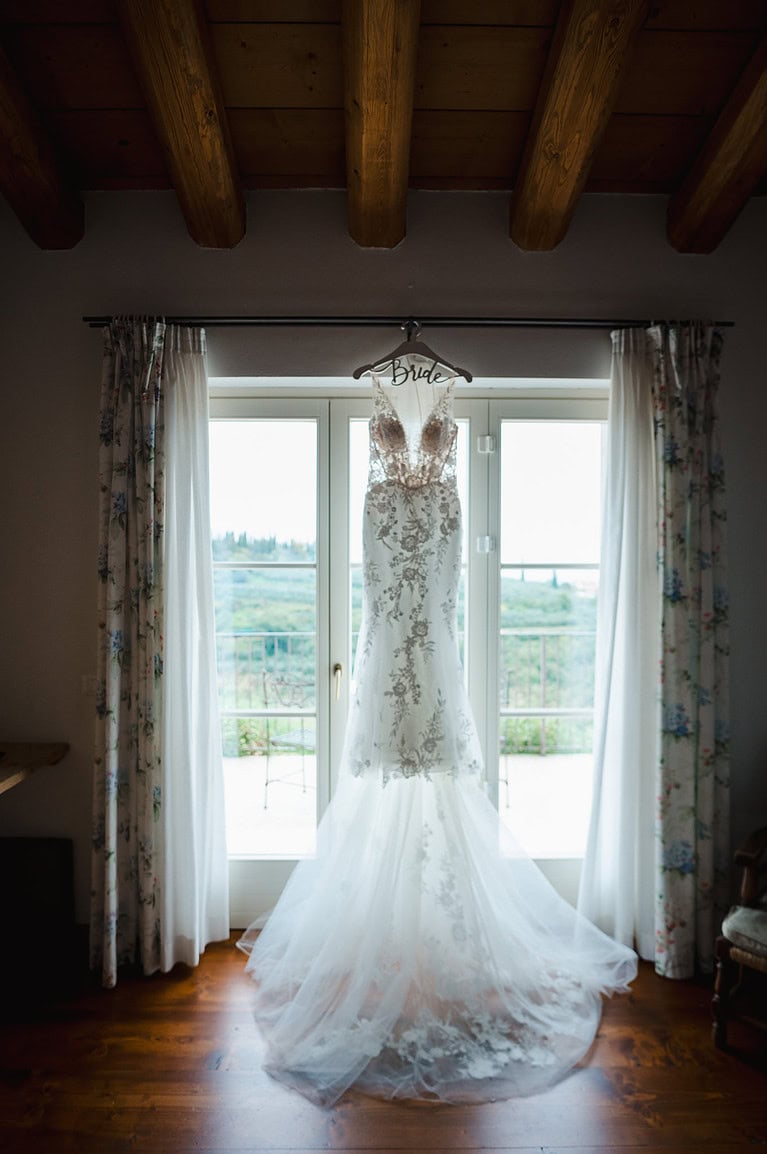 Wedding Dress hanging up in the doorway with a view across the Italian hill tops
