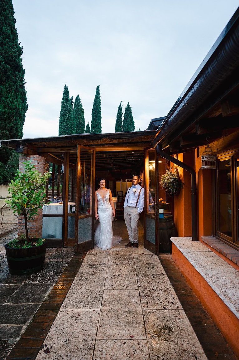 Bride and groom leaning against doorway taking shelter from the rain at their Verona Wedding