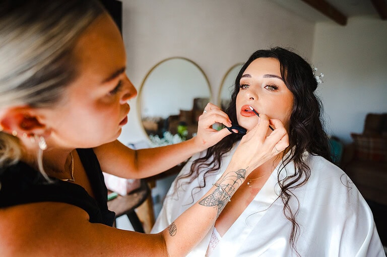 Bride having her makeup done on her wedding morning
