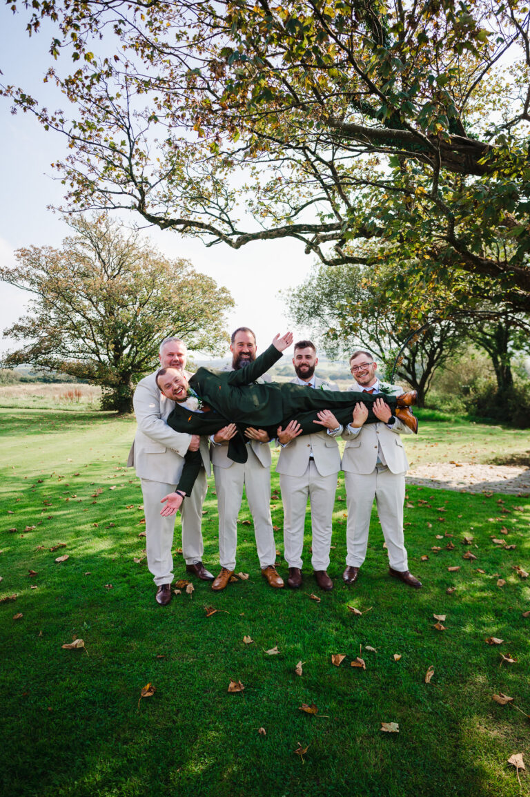 Groom being held up by groomsmen
