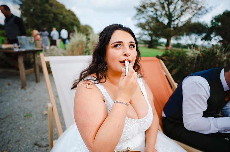 Bride pulling a face as she applies lipstick