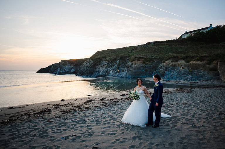 Newlyweds walking a long the beach at sunset