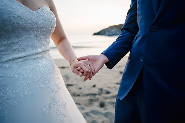 Holding hands on the beach as newlyweds