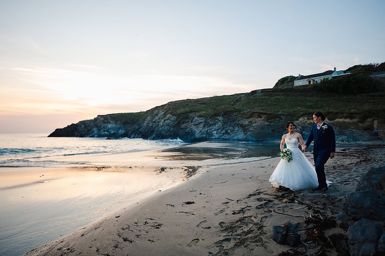 Sunset wedding walks along a beach in Cornwall