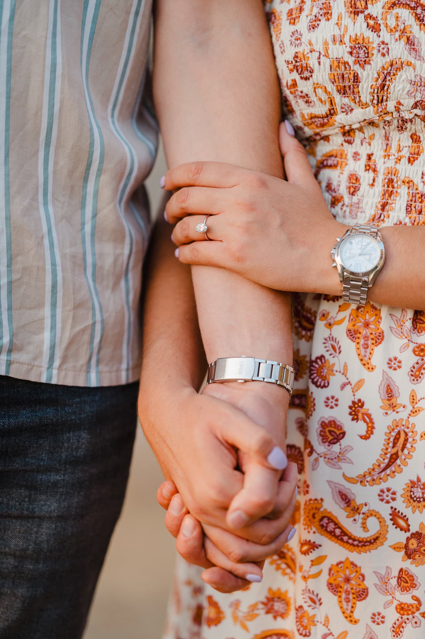 Hands holding hands as the happy couple show off their engagement photos by Cornwall engagement photographer, Jake Timms Photography