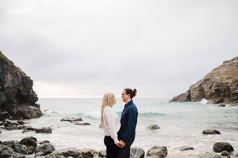 WIth the sea in the background, the newly engaged couple place hands in hand and look into each others eyes as they enjoy their Chapel Porth engagement photo shoot