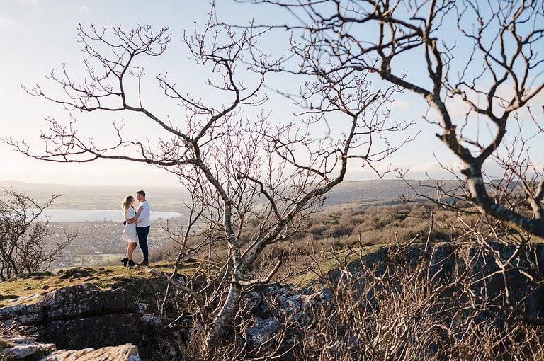 Surrounded by bare tree branches on Cheddar Gorge Valley by Somerset Engagement Photographer, Jake Timms Photography
