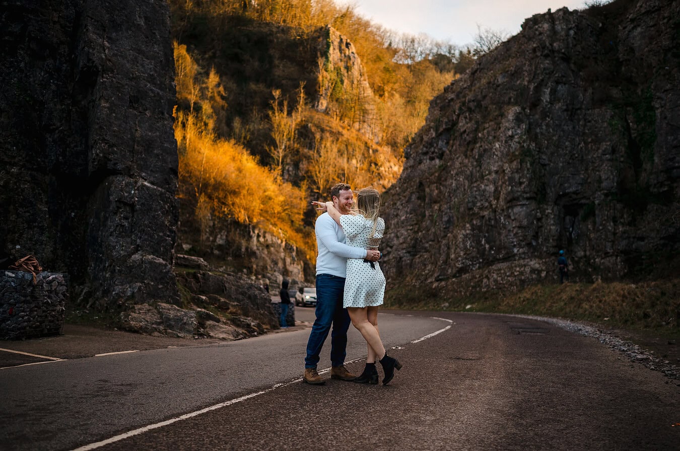 Standing in the middle of the road in the gorge itself as rays of golden sun hit the back cliff edge By Somerset Engagement Photographer, Jake Timms Photography