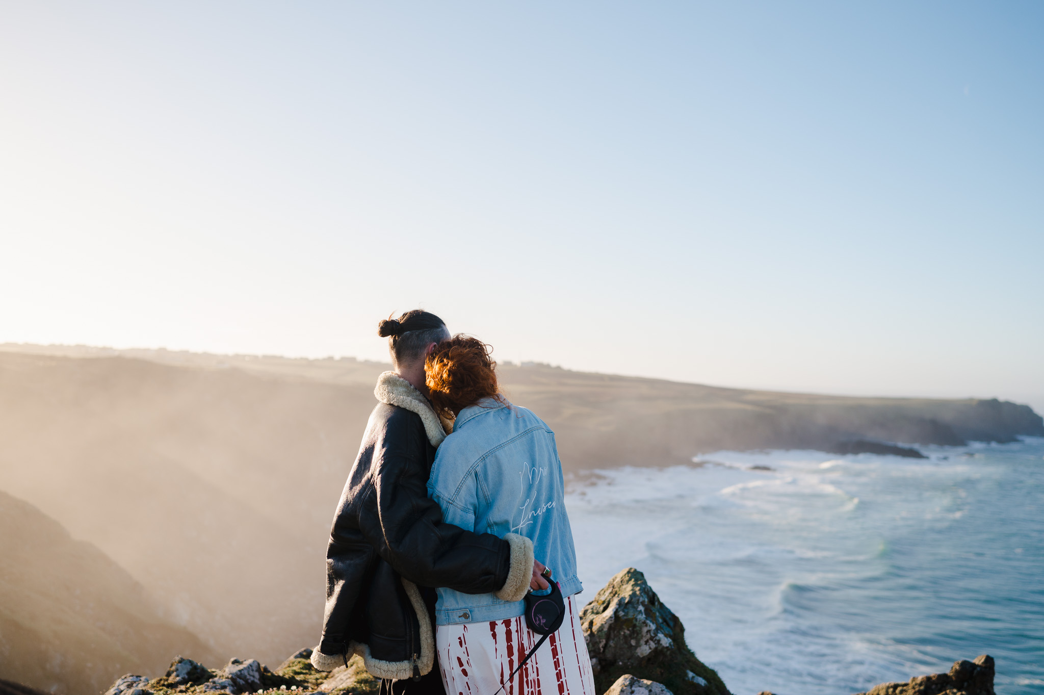 The couple hug and look out to sea during the sunrise over Kynance Cove
