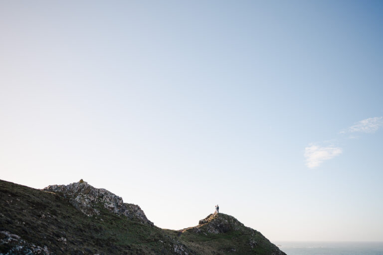 A snippet of land as the couple stand at the end of the rocky Cornish coast during their Kynance Cove Engagement photo shoot