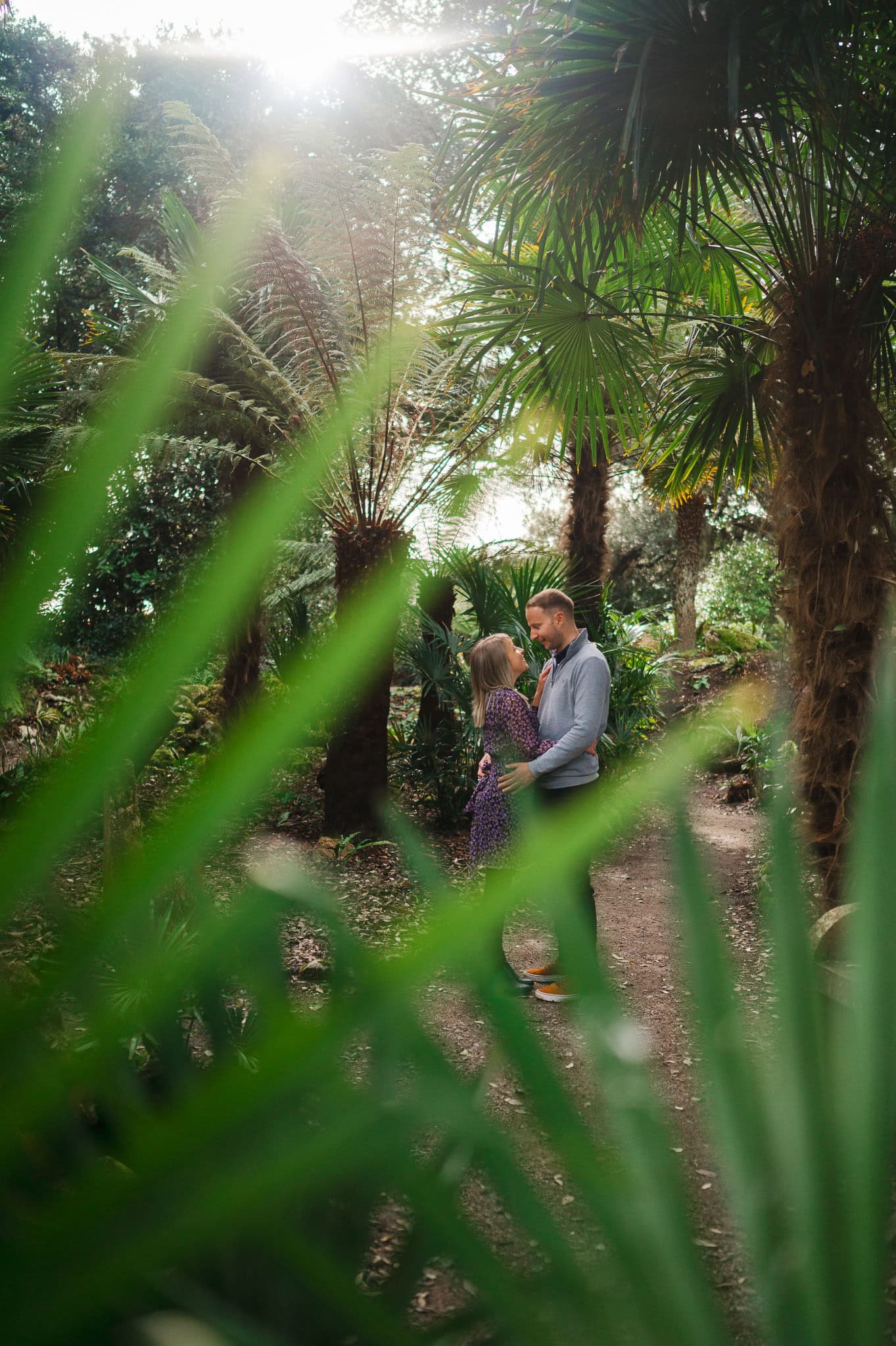 Looking through the fern towards the happily engaged couple during their Mount Edge Combe Engagement Photo Shoot