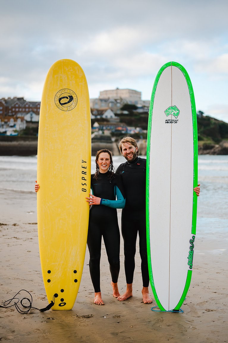 Standing side by side with their surfboards in the sand