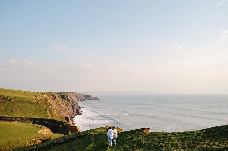 Walking along the Cornish coastpath as the sunsets before heading down for their engagement photo shoot at Sandymouth, Cornwall