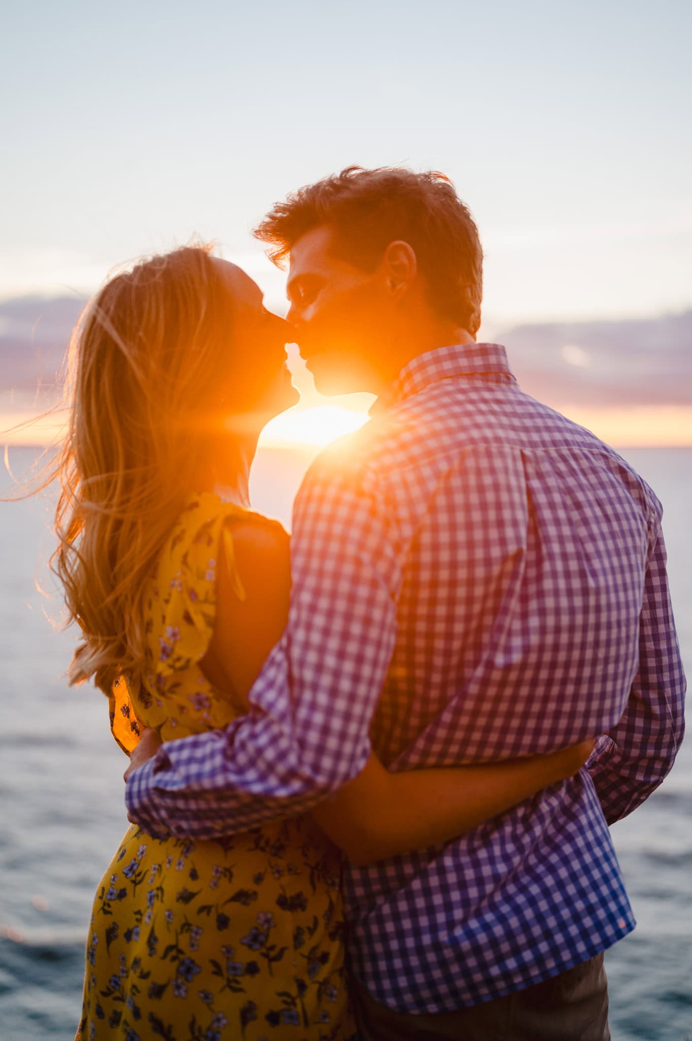 Going in for a kiss as the red glow of the sunset pierces through. By Cornwall Engagement Photographer, Jake Timms Photography
