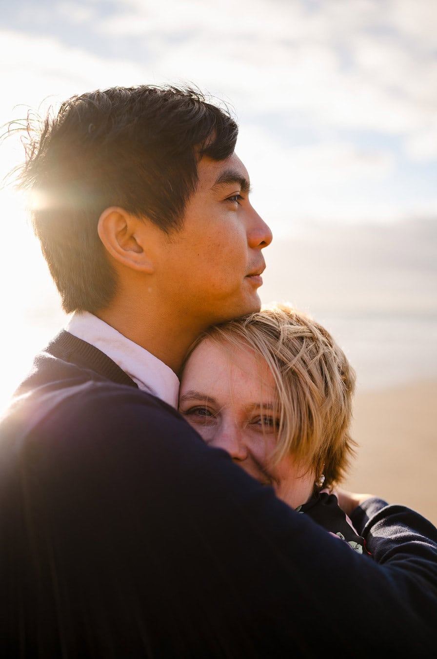 Looking over his shoulder during the happy couples engagement photo shoot at Whitsand Bay