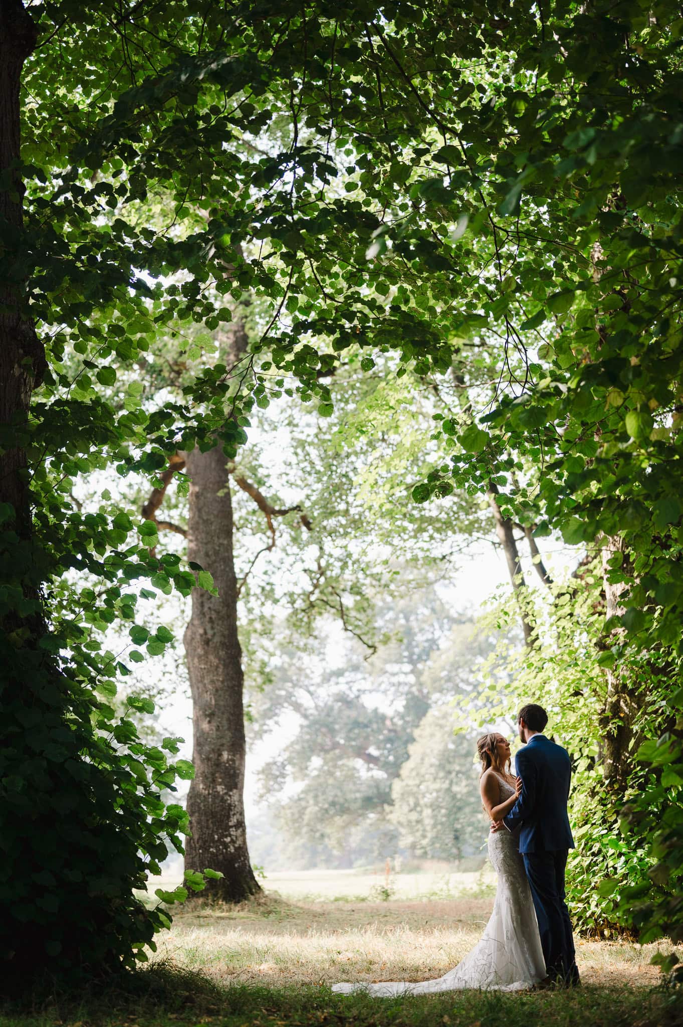 Happy couple pose underneath a forrest canopy at Rockbeare Manor by Devon Wedding Photographer, Jake Timms Photography