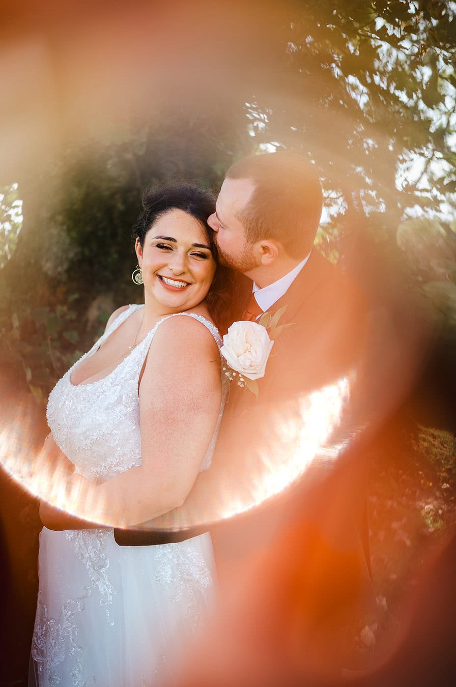 A happy couple surrounded by a circle of bright golden light as they happily laugh during there couple photos