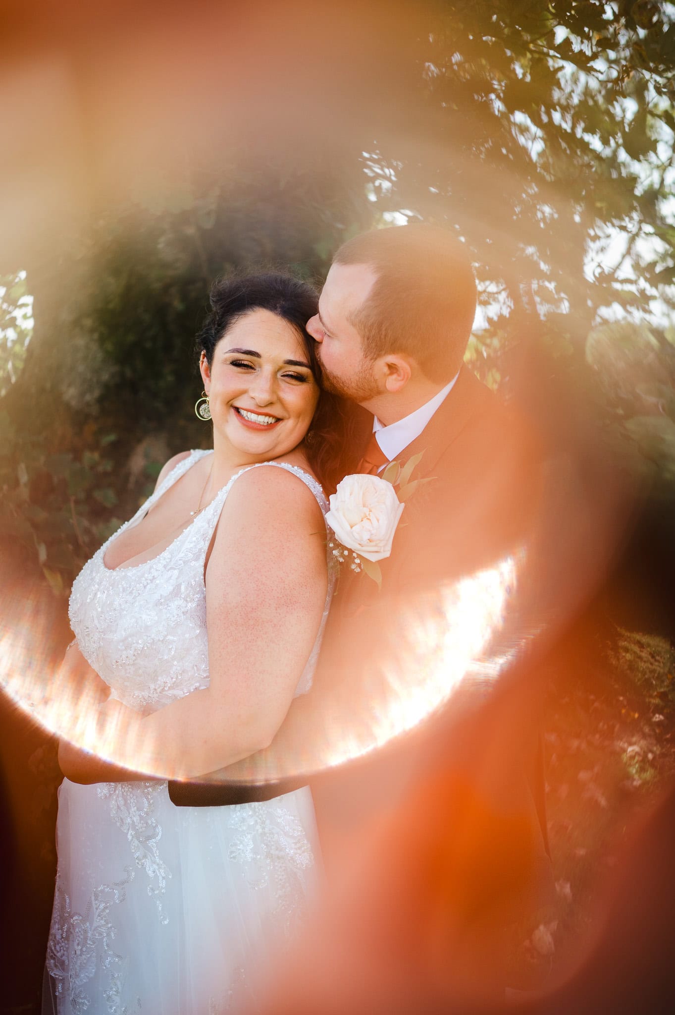 Bride laughs and smiles as she gets a kiss on the forehead by Bristol Wedding Photographer, Jake Timms Photography