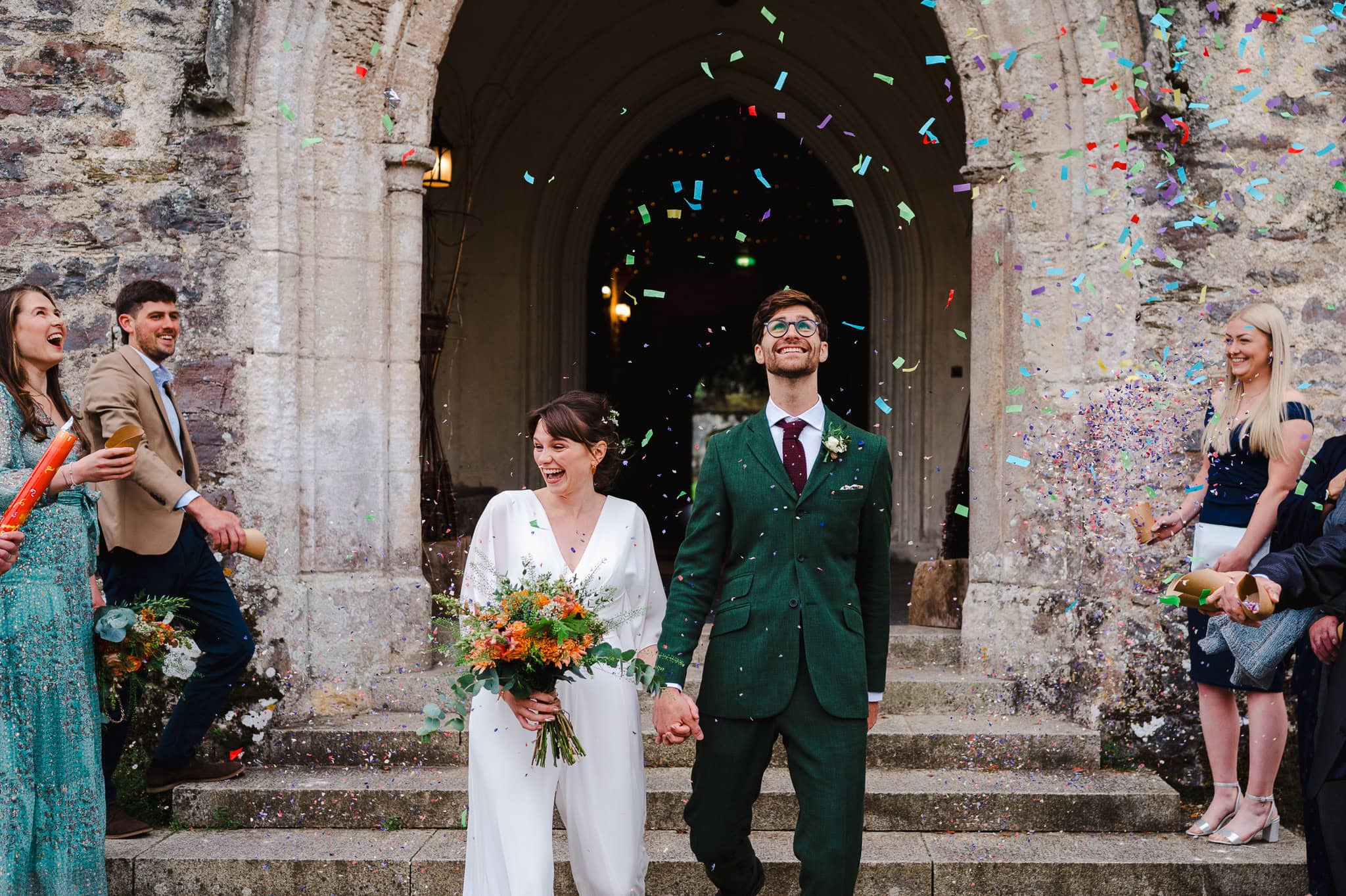 Wedding confetti falls over the happy couple as they exit through the grand doorway by Somerset Wedding Photographer, Jake Timms Photography